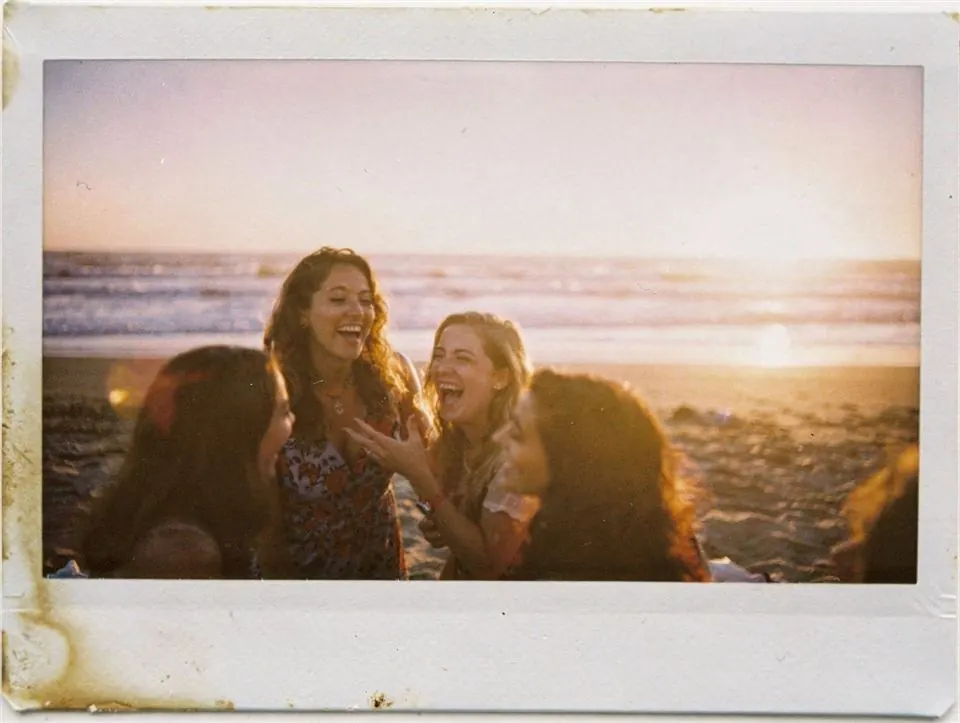 Teman-teman tertawa di pantai saat golden hour
